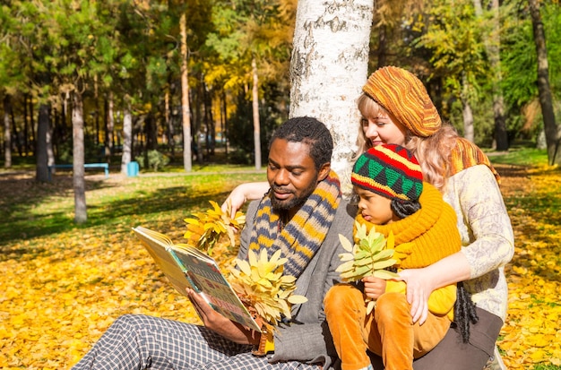 Happy family in autumn park African American family black father mom and child boy on nature in fall