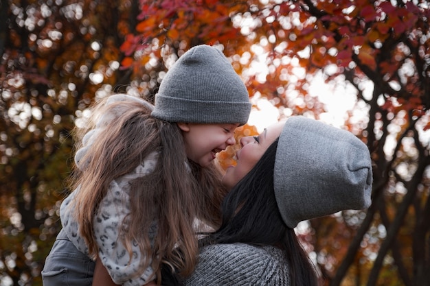 Happy family on an autumn walk. Mother and daughter walking in the park and enjoying the beautiful autumn nature.