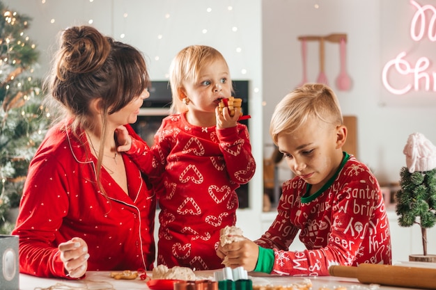 幸せな家族はクリスマスの赤ちゃんが食べるためにクッキーを焼く