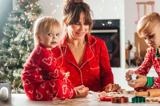 幸せな家族は子供がカメラを見てクリスマスのためにクッキーを焼く