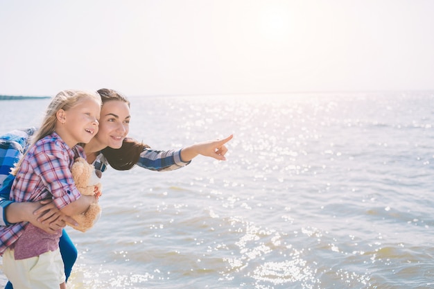 ビーチで幸せな家族。夏休みを楽しんでいる人。母と子の青い海と空の背景。休日旅行のコンセプト