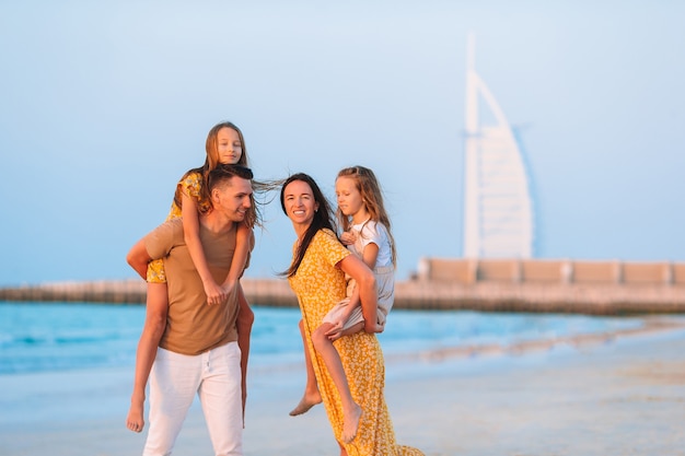 Famiglia felice sulla spiaggia alle vacanze estive con burj al arab a dubai, emirati arabi uniti.