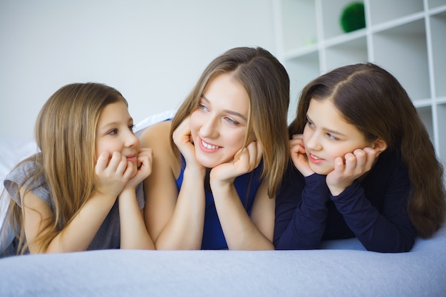 Happy family on the bed. Children with their mother in the bedroom.