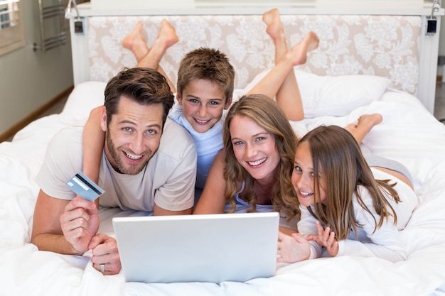 Happy family on the bed using laptop