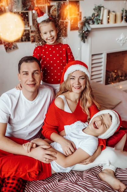 Famiglia felice sul letto in attesa del nuovo anno e buon natale