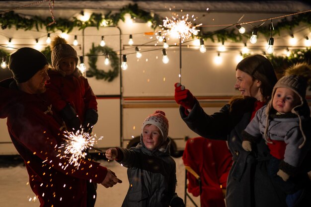 Photo happy family celebrates christmas in nature and holds sparklers parents with three sons travels in