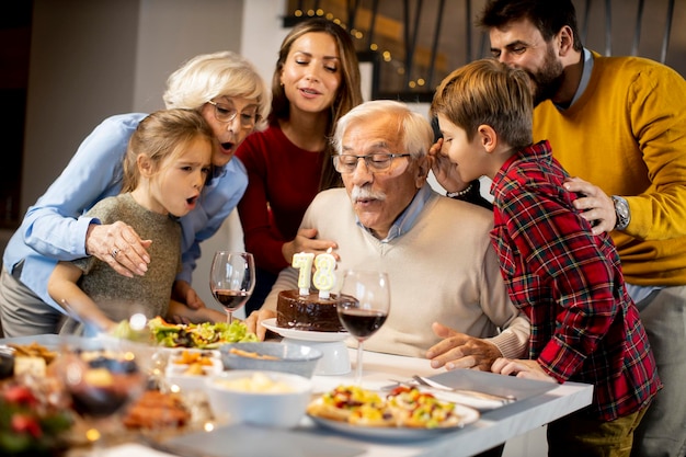 Happy family celebrating grandfather birthday with cake and candles at home