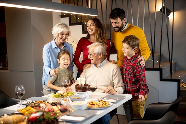 Happy family celebrating grandfather birthday with cake and candles at home