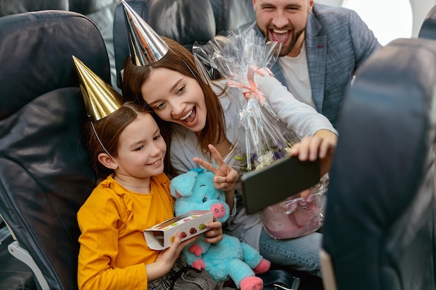 Happy family celebrating kid birthday and making selfie in plane