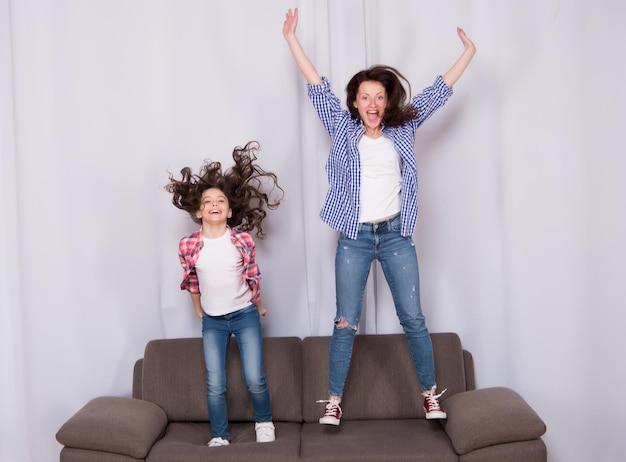 Happy family celebrating mothers day Happy mother and daughter jumping on sofa Mother and child enjoying happy mothers day Pretty woman and little girl on mothers day International mothers day