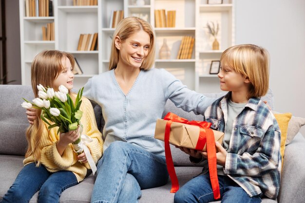 Happy family celebrating Mothers Day at home Kids are gifting their mom