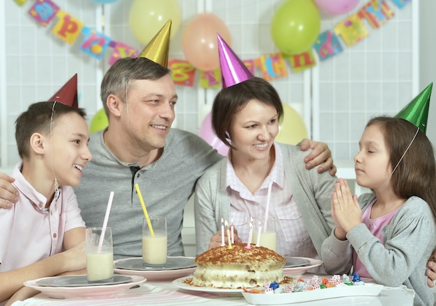 Happy family celebrationg birthday at home with cake