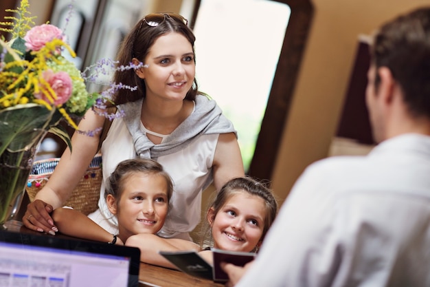 Happy family checking in hotel at reception desk