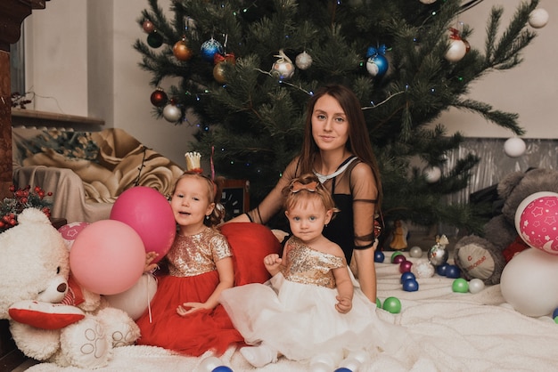 Happy family children celebrating New Year and Christmas at decorated Christmas tree and garlands