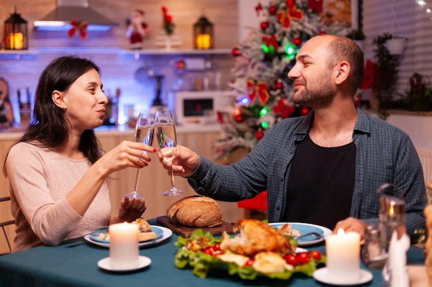 Happy family clinking glass of wine sitting at dining table