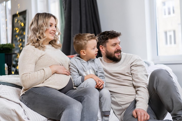 Happy family concept Mother father and little son have fun at home Caucasian family indoors Pregnant mom beard dad and funny little boy