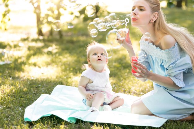 Happy family concept with young mother playing with her baby girl and making soap bubble