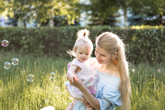 Happy family concept with young mother playing with her baby girl and making soap bubble