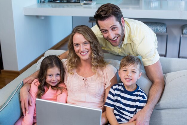 Happy family on the couch together using laptop