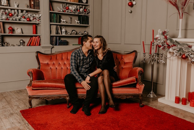 Happy family couple celebrating New Year and Christmas at decorated Christmas tree and garlands