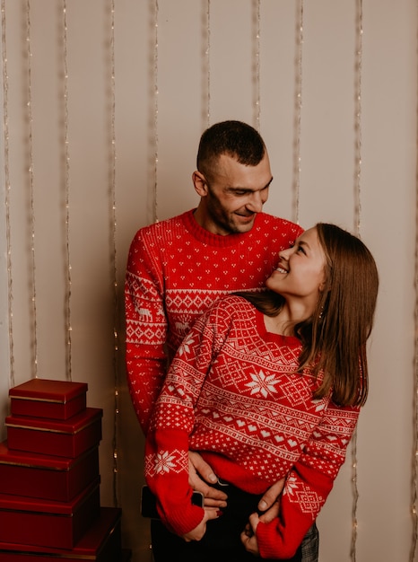 Happy family couple celebrating New Year and Christmas at decorated Christmas tree and garlands