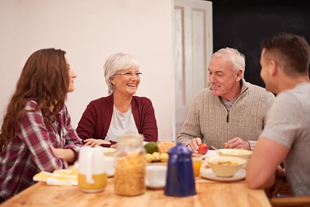 Happy family couple and senior parents at breakfast for talking bonding and laugh together in the morning Food elderly mother and father with adults eating fruit cereal and conversation in home