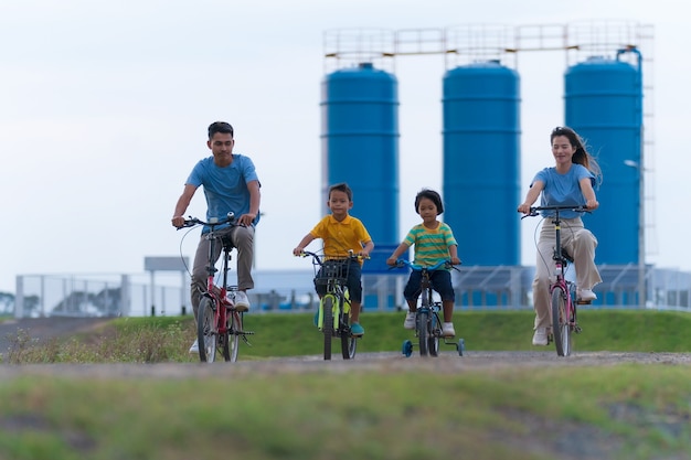 Happy family cycling on bikes outdoors, active parents with children have fun, family sport and fitness, vacation, relax in countryside