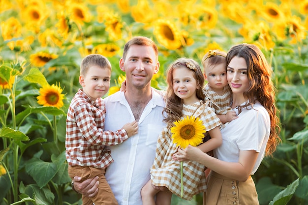 Photo happy family, dad, daughter and son have fun, play among blooming sunflowers in the fresh air