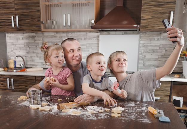 Happy family dad mom and two kids take selfies in the kitchen while making cookies. cooking together happy family relationships