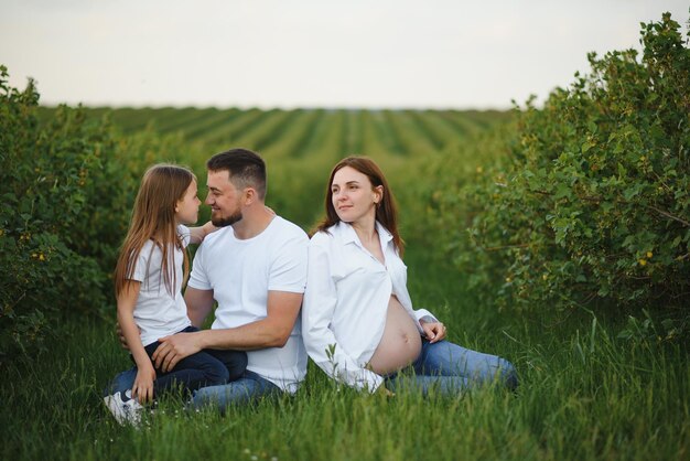 Happy family Dad pregnant mom and little daughter play games at sunset in summer in park