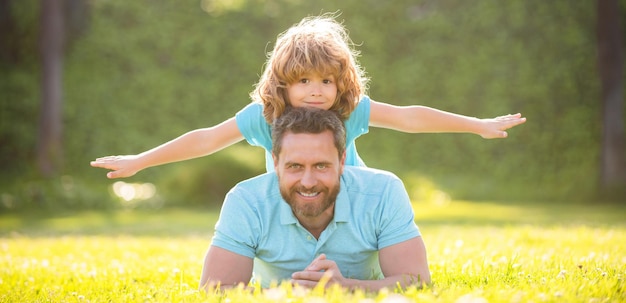 Happy family of dad and son boy relax in summer park green grass fatherhood