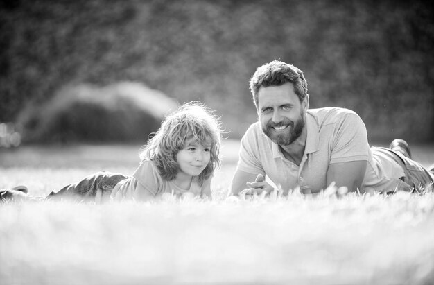 Happy family of daddy and son kid relax in summer park green grass fathers day