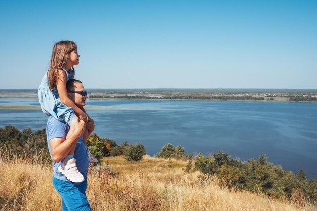 A happy family Daughter sitting on the shoulders of her father outdoors