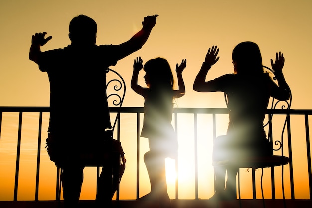 Foto famiglia felice all'alba del fondo della siluetta del mare