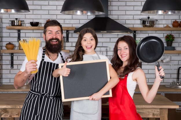 Photo happy family day friendly family in kitchen healthy food at home kid chef cook dinner copy space do everything together everyday winners mother and father cooking with daughter organic food