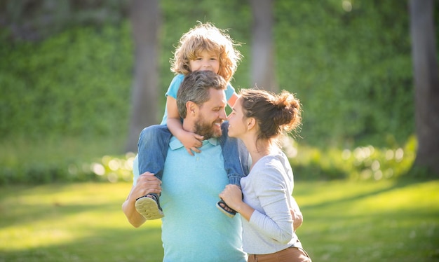 Happy family day Mother and father carrying son on shoulders Family day Parents and boy child