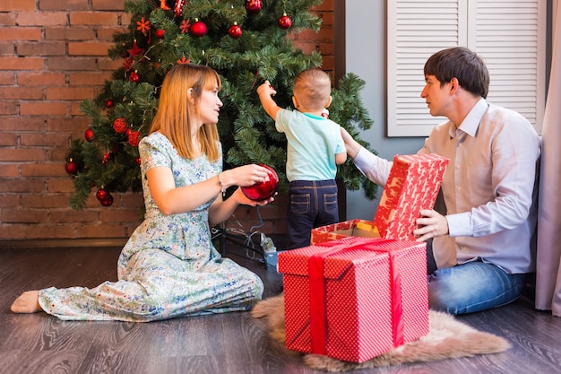 写真 一緒にクリスマスツリーを飾る幸せな家族。父、母、息子。かわいい子。キッド。