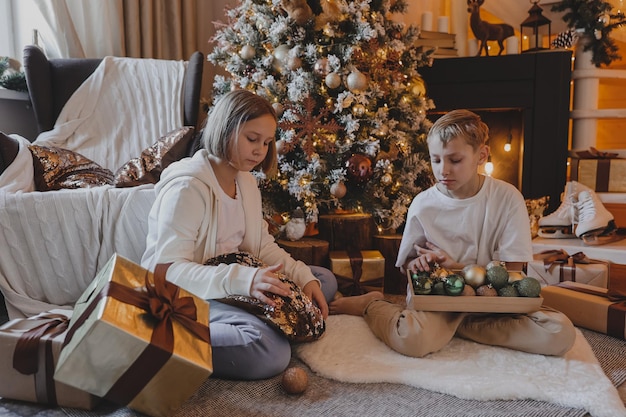 Famiglia felice che decora un albero di natale con palline e regali in soggiorno, buon natale e vacanze di capodanno. famiglia, vacanze invernali e concetto di persone