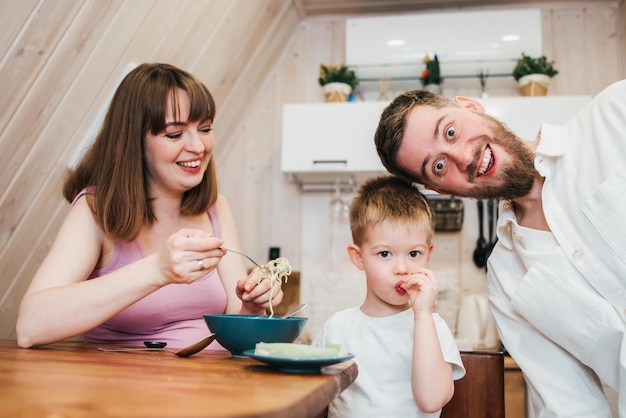 Happy family eating pasta in the kitchen