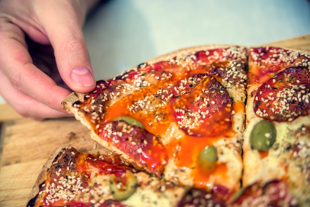 Happy family eating pizza on the wooden table. Hands taking pizza from table, closeup. food, leisure and friendship concept