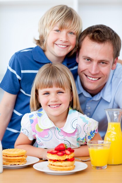 Happy family eating waffles with strawberries