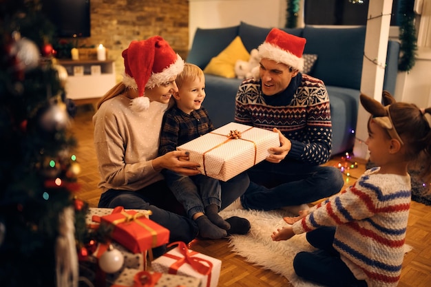 家でクリスマスイブに贈り物を交換する幸せな家族