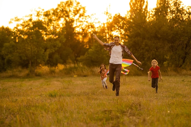 happy family father and child daughter run with a kite on meadow