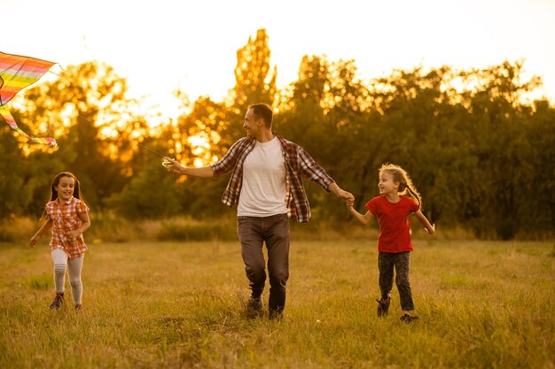 happy family father and child daughter run with a kite on meadow