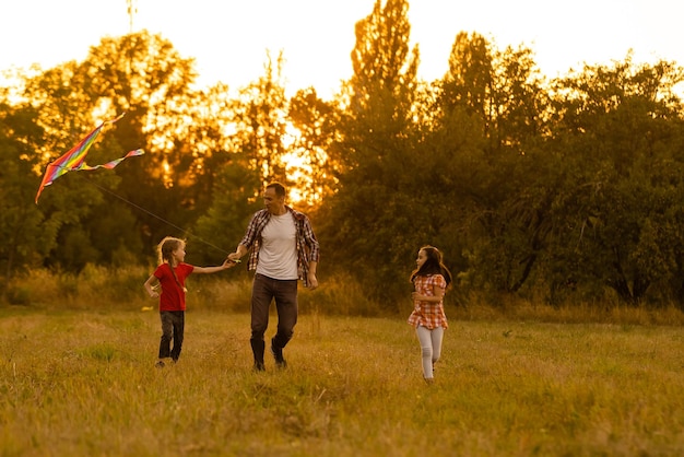 Il padre di famiglia felice e la figlia del bambino corrono con un aquilone sul prato