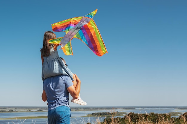 自然の中で幸せな家族の父と子が凧を空に飛ばしている