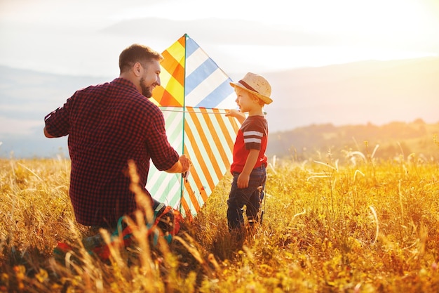 Happy family father and child son launch kite on meadow