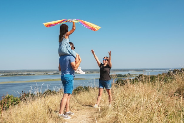 Happy family father mother and child play with kite on nature