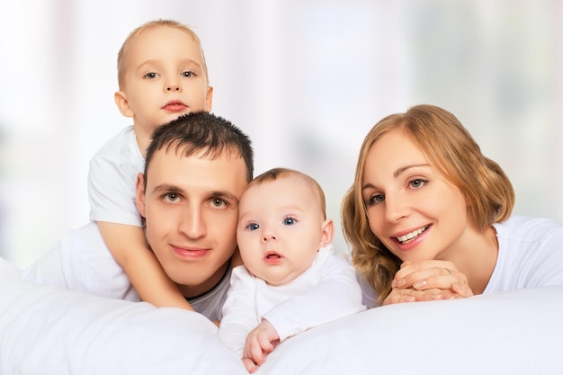 Happy family of father mother and children in bed