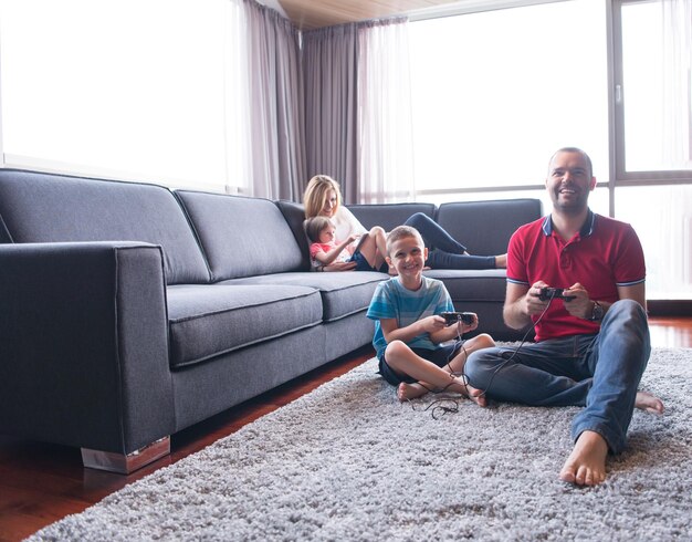 Happy family. Father, mother and children playing a video game Father and son playing video games together on the floor